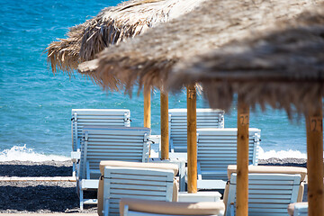 Image showing beach with umbrellas and deck chairs by the sea in Santorini