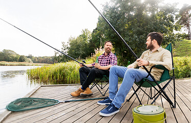 Image showing male friends fishing and drinking beer on lake