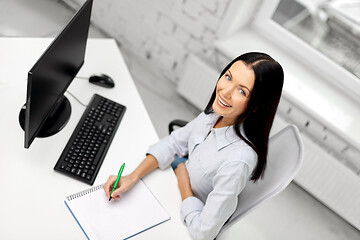 Image showing businesswoman writing to notebook at office