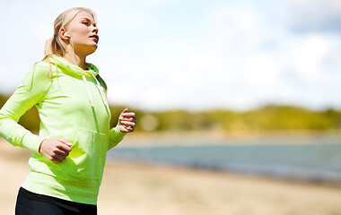 Image showing woman with earphones running at park