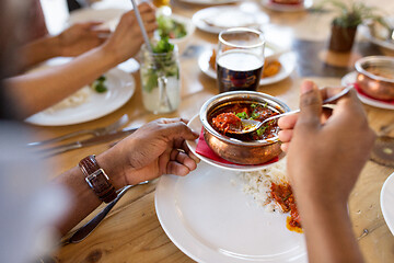 Image showing african man eating with friends at restaurant