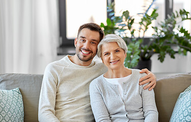 Image showing senior mother with adult son hugging at home