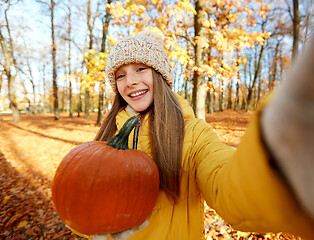 Image showing girl with pumpkin taking selfie at autumn park