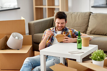 Image showing smiling man eating takeaway food at new home