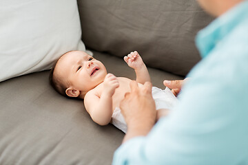 Image showing middle aged father changing baby\'s diaper at home