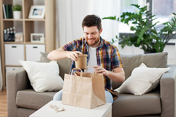 Image showing smiling man unpacking takeaway food at home