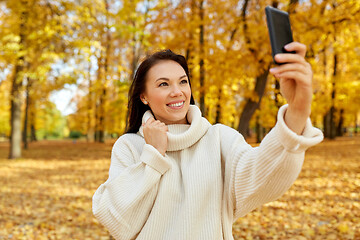 Image showing woman taking selfie by smartphone at autumn park