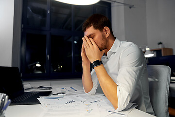 Image showing tired businessman working at night office