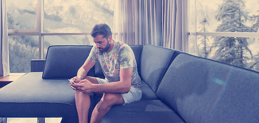 Image showing young casual man using a mobile phone at home