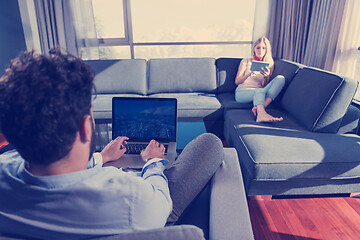 Image showing couple relaxing at  home using tablet and laptop computers