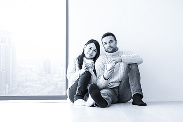 Image showing multiethnic couple enjoying morning coffee by the window