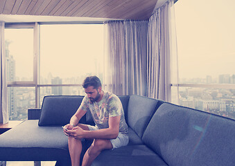 Image showing young casual man using a mobile phone at home