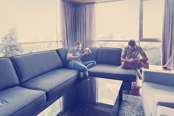 Image showing two young men using a mobile phones  at home