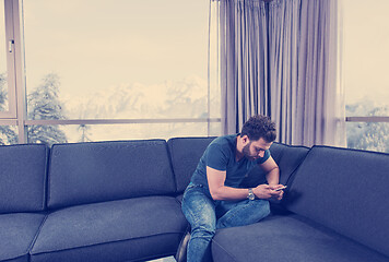 Image showing young casual man using a mobile phone at home