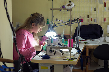 Image showing Fashion designer clothes sews on sewing machine by light lamp in workshop