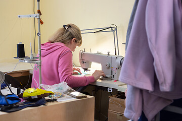 Image showing Girl sews on a professional sewing machine in the workshop