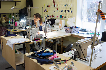 Image showing girl with a bored and dejected look at the workplace in a sewing workshop