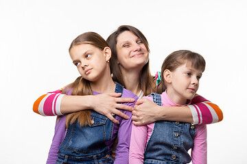 Image showing Mom happily hugs children, children turned away from mom
