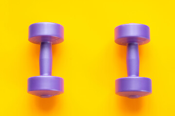 Image showing Two purple dumbbells lie separately on a yellow background