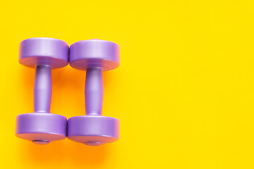 Image showing Two purple dumbbells lie next to a yellow background