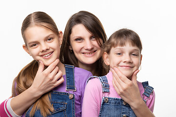 Image showing Mom cheerfully holds the children by the chin and looks in the frame