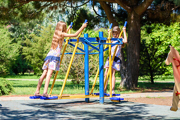 Image showing Two girls warm up on exercise machines in the park