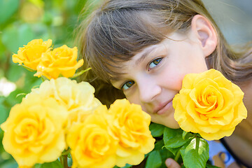 Image showing Portrait of a girl of nine years with yellow roses