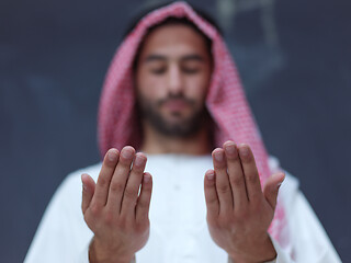 Image showing arabian man making traditional prayer to God, keeps hands in pra