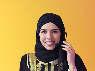 Image showing portrait of muslim woman with headset on yellow background