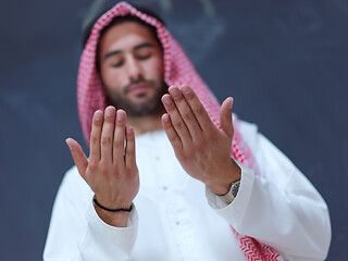 Image showing arabian man making traditional prayer to God, keeps hands in pra