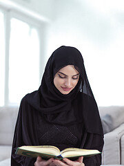 Image showing young muslim woman reading Quran at home