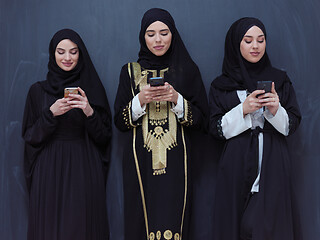 Image showing muslim women using mobile phone in front of black chalkboard