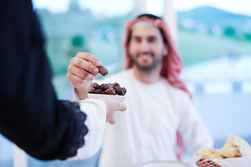 Image showing Muslim family having Iftar dinner eating dates to break feast