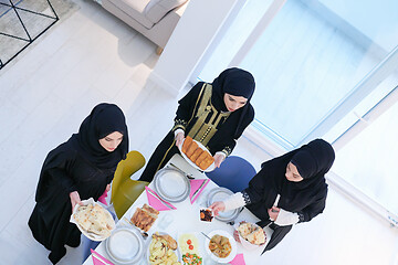 Image showing young muslim girls serving food on the table for iftar dinner to