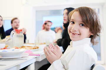 Image showing little muslim boy praying with family before iftar dinner