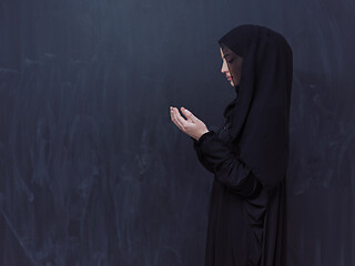 Image showing muslim woman making traditional prayer to God in front of black 