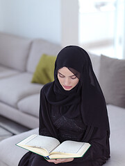 Image showing young muslim woman reading Quran at home