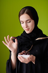 Image showing Woman in Abaya Holding a Date Fruit and glass of water