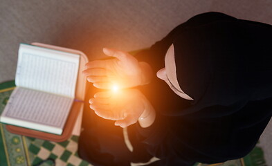 Image showing Middle eastern woman praying and reading the holy Quran