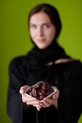 Image showing Woman in Abaya Holding a Date Fruit and glass of water