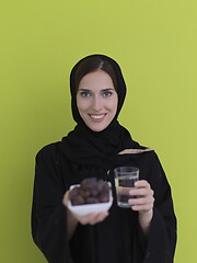 Image showing Woman in Abaya Holding a Date Fruit and glass of water