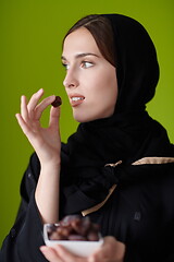 Image showing Woman in Abaya Holding a Date Fruit and glass of water