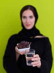 Image showing Woman in Abaya Holding a Date Fruit and glass of water