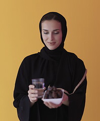 Image showing Woman in Abaya Holding a Date Fruit and glass of water