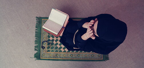 Image showing Middle eastern woman praying and reading the holy Quran