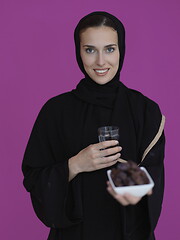 Image showing Woman in Abaya Holding a Date Fruit and glass of water