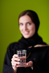 Image showing Woman in Abaya Holding a Date Fruit and glass of water