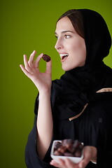 Image showing Woman in Abaya Holding a Date Fruit and glass of water