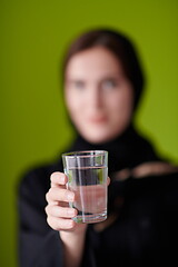 Image showing Woman in Abaya Holding a Date Fruit and glass of water