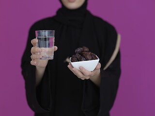 Image showing Woman in Abaya Holding a Date Fruit and glass of water